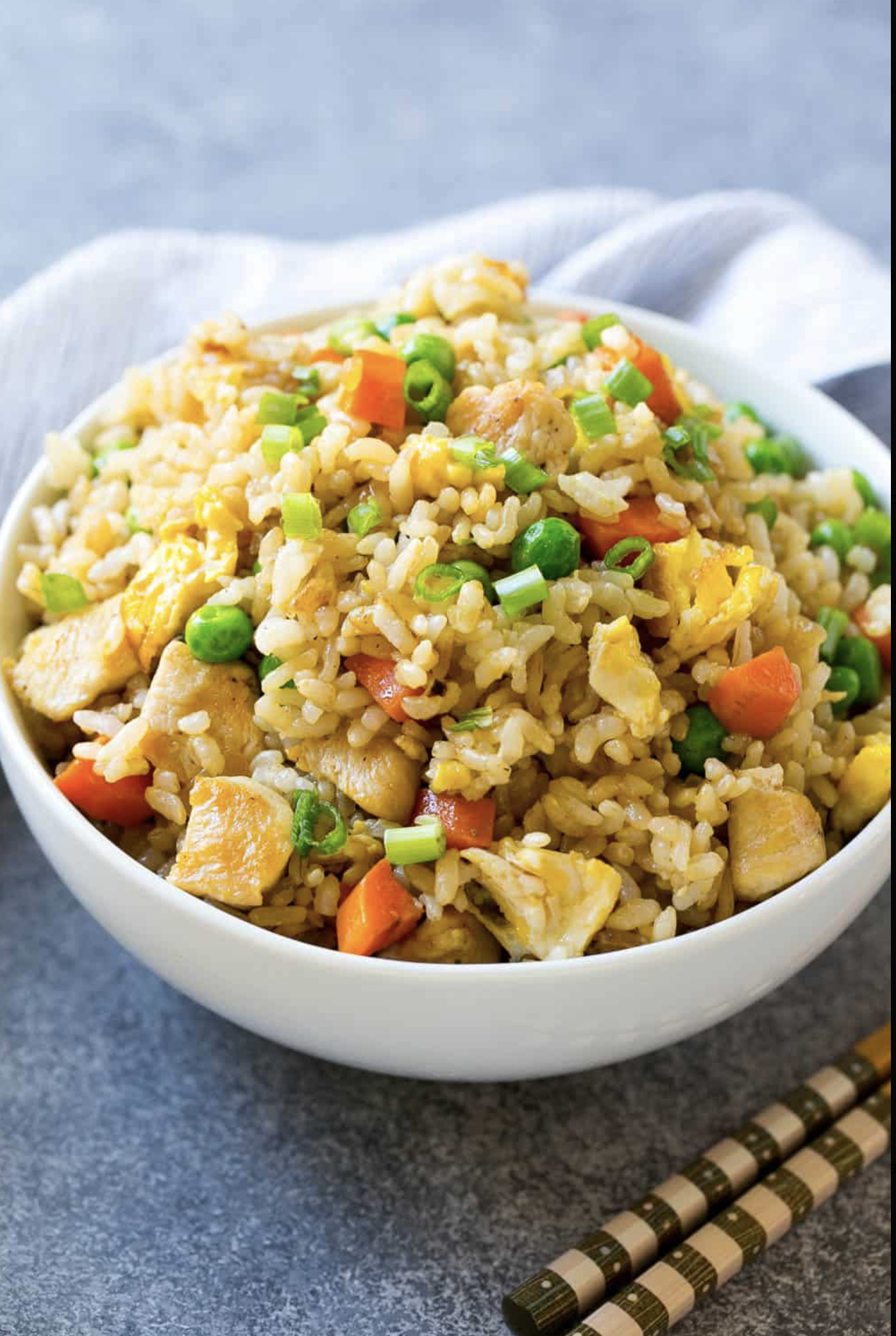 bowl of cauliflower fried rice with napkin and wooden spoon and for