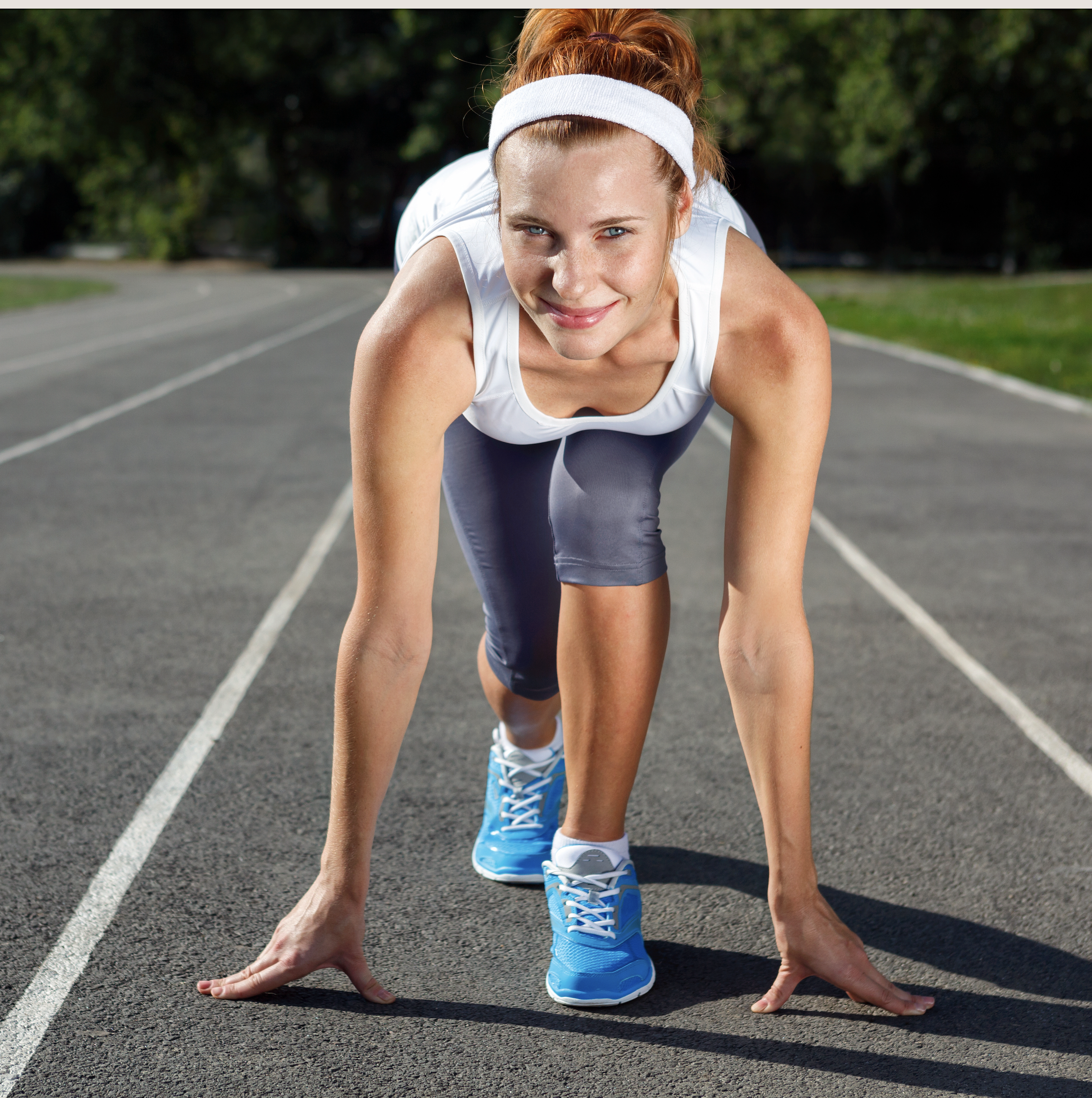 woman in fitness wear and sneakers at the starting line of a track