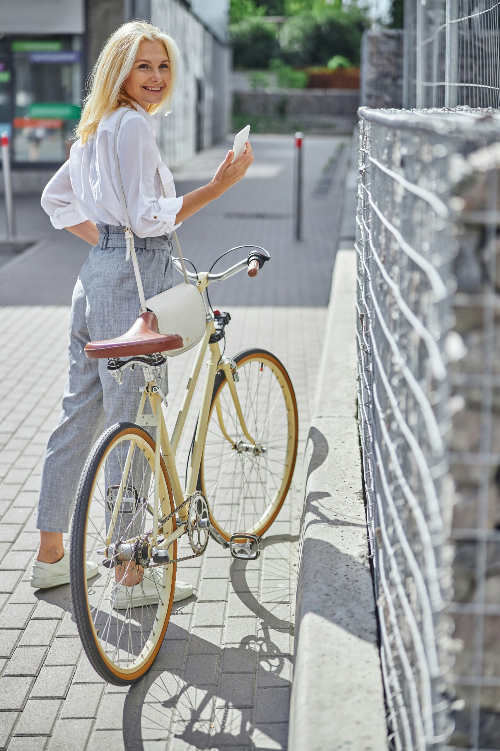 women in white shirt and jeans standing beside a yellow bike